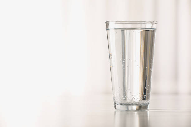 istock Glass with water on table against blurred background. Space for text 1717382989