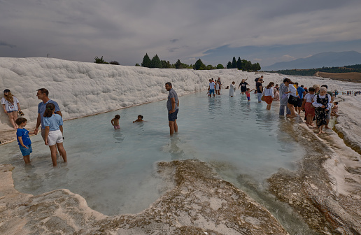 Pamukkale, Denizli Turkey, Travertines of Pamukkale, a Natural thermal pools surrounded by white limestone, accessed by a walk over rough rocks.