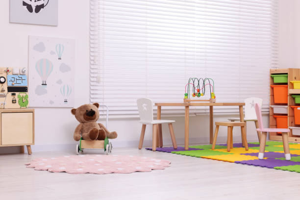 Stylish kindergarten interior with table, shelving unit and different toys