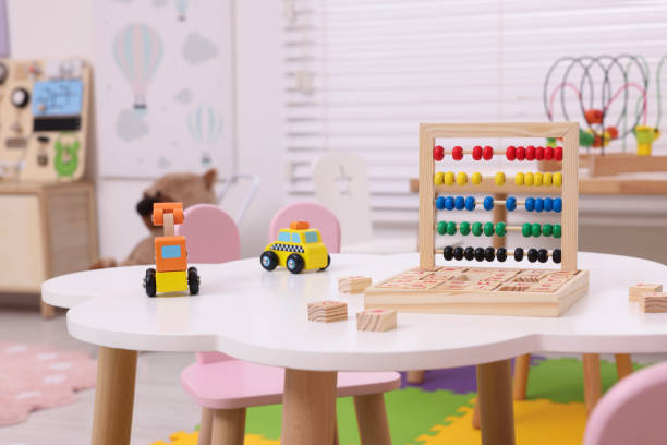 verschiedene spielsachen auf dem tisch im spielzimmer. interieur des kindergartens - kinderbetreuung stock-fotos und bilder