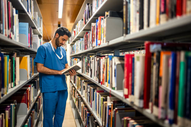 un pasante masculino que investiga en la biblioteca para estudiar - male nurse nurse aspirations learning fotografías e imágenes de stock
