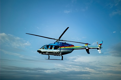 Blue and white helicopter in flight isolated against white background