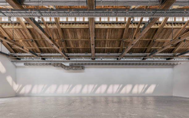 vista lateral de um grande e longo interior branco vazio da galeria/showroom com grandes paredes brancas vazias para eventos ou exposição de obras de arte, e uma construção industrial de teto com tubos de ventilação, vigas de madeira e refletores (eq - cement floor frame abandoned architecture - fotografias e filmes do acervo