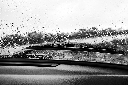 Raindrops on the windshield of a car, view from the inside. Black and white photo