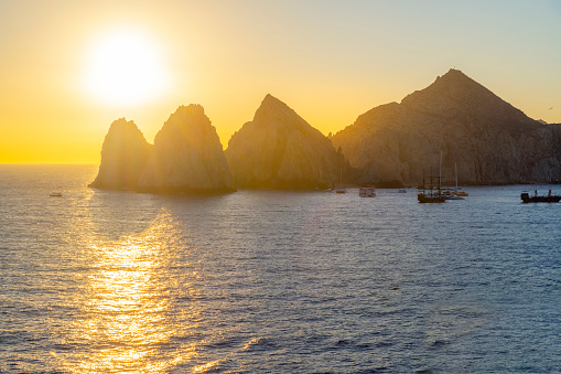 The morning sun appears over the El Arco coastal rocks at the Mexican port city of Cabo San Lucas, Mexico.