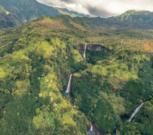 Several waterfalls within a canyon of Hawaii taken from overhead while taking a helicopter tour on the island of Kauai