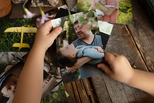 Photo printing concept, family memories. Preschooler boy holds printed photos.