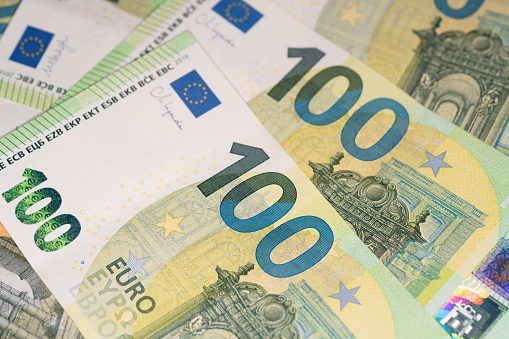 High angle view of hand holding Euro banknotes and coins. Bill and pocket calculator are out of focus at background and complete the composition. High resolution 42Mp studio digital capture taken with Sony A7rII and Sony FE 90mm f2.8 macro G OSS lens