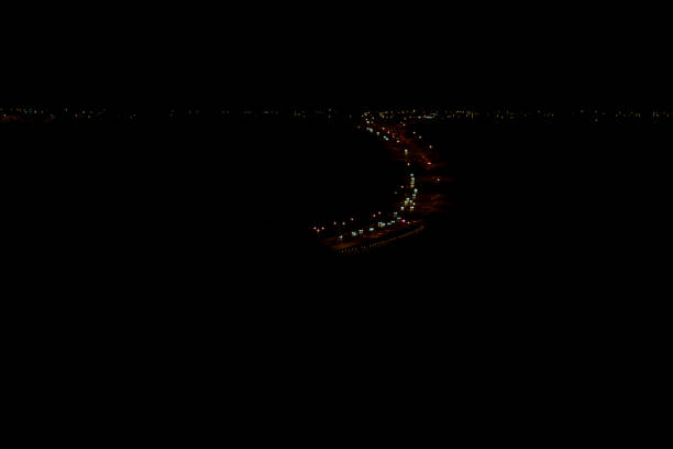 Photo shows Whoop-Up Drive in Lethbridge at night.  This is a curved stretch of roadway that takes traffic through the Oldman River Valley coulees, being the main fairway connecting the South and West sides of the city.  Photo is looking west, showing lights from businesses and homes on the west side, appearing in an ’s’ shape.