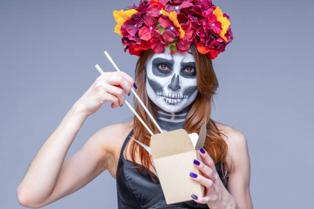 Woman in death costume holding paper box, wok noodle sticks, takeaway hot offer stock photo
