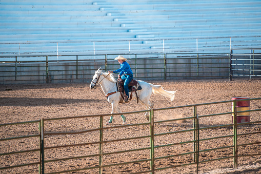 Cowgirl riding a horse in a rodeo arena. About to barrel race.