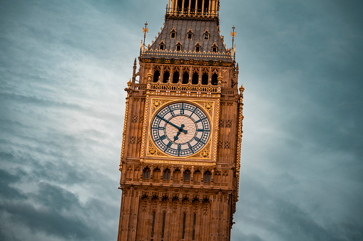 A close-up of the Big Ben clock face illuminated by the setting sun.