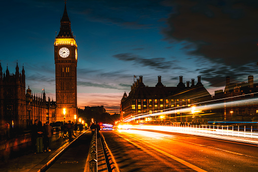 Big Ben and Westminster Bridge at night with the lights trails of the cars passing by.