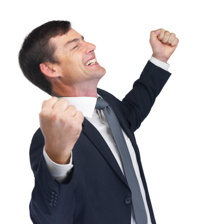 excited young businessman in navy blue suit holding fists in the air, laughing and celebrating victory, standing and posing isolated on white background in studio, portrait