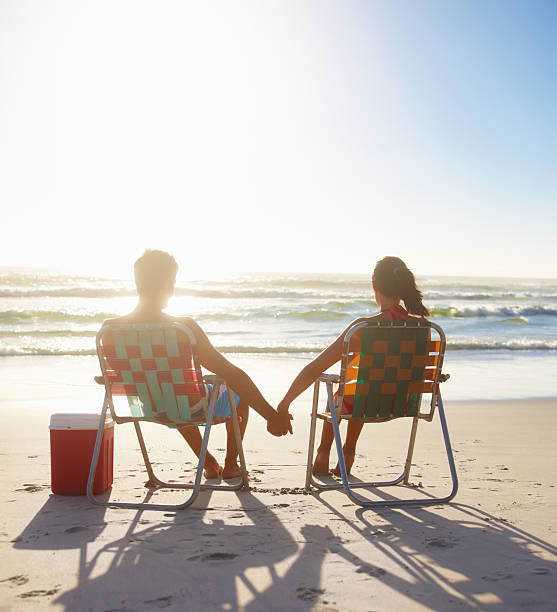 サンセット：若いカップル、夏のバケーションをお楽しみいただけます。 - deck chair ストックフォトと画像