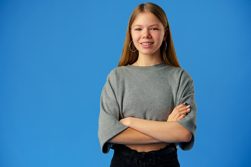 Happy teenager, positive smiling girl on blue background in studio close up