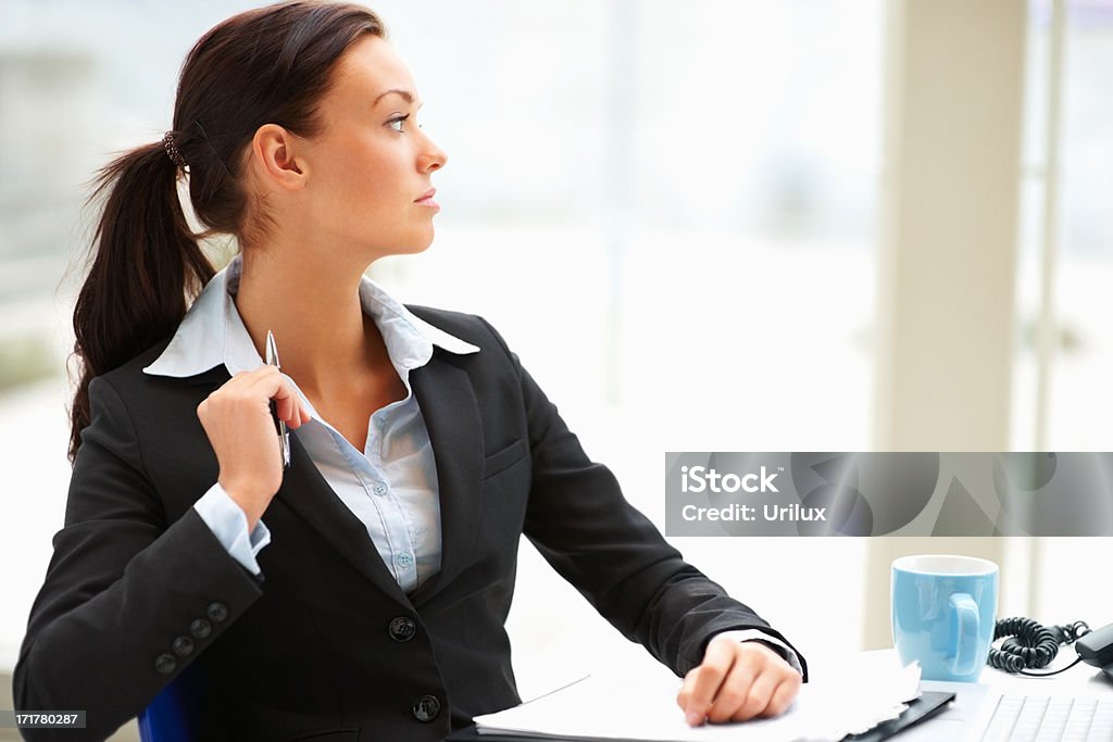 Businesswoman in suit sitting in the office and thinking  Blue Stock Photo