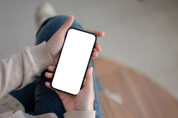 istock Top view image of a white-screen smartphone mockup is in a woman's hands. 1717826904