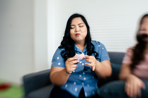 Close up of overweight happy woman biting donut in living room