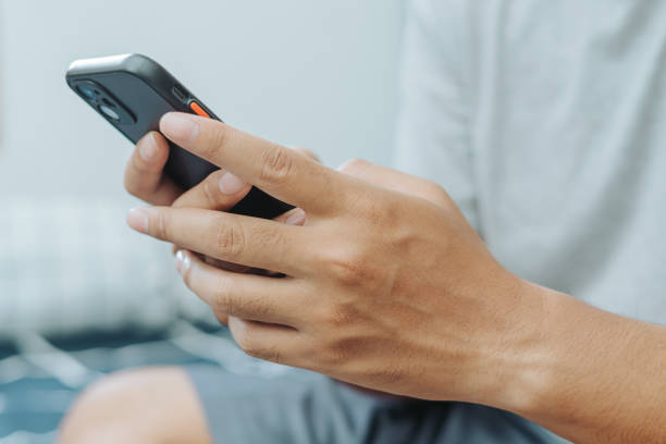istock Hands of Asian man holding checking touching scrolling smartphone from bed room 1717866745