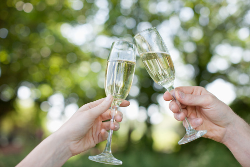 Two wineglasses standing together over blurred green nature background. Celebration concept. Champagne theme