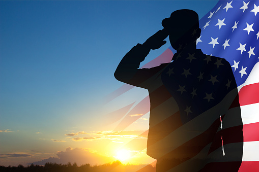 Silhouette of soldier with USA flag against the sunset. Greeting card for Veterans Day, Memorial Day, Independence Day