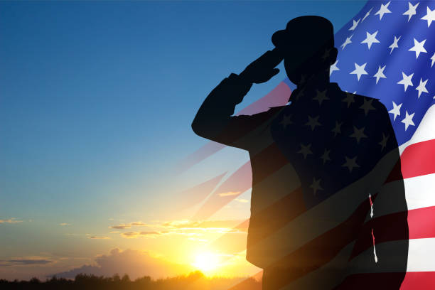 Silhueta do soldado com bandeira dos EUA contra o pôr do sol - foto de acervo