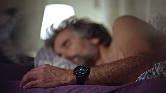Man sleeping, a smart watch monitoring health chart.