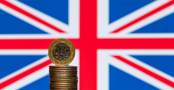 1 British pound coin with the British flag in the background