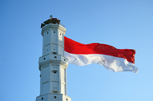 indonesian national flag on lighthouse with blue sky background