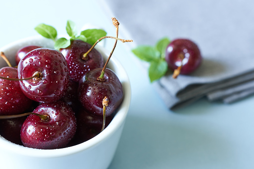 A bowl of cherries on the table with a napkin. The concept is to make breakfast.