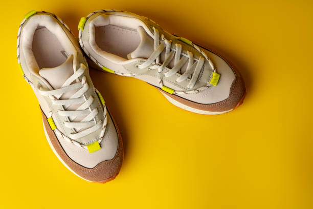 istock Beige sport running shoes on yellow studio background 1718049576