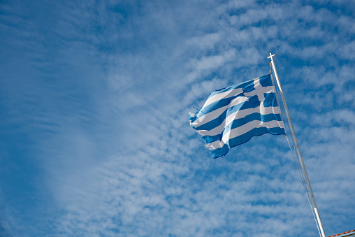 Greek blue and white flag waving against a blue dramatic cloudy sky.