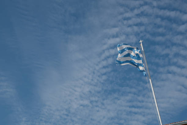 istock Greek blue and white flag waving against a blue dramatic cloudy sky 1718065061