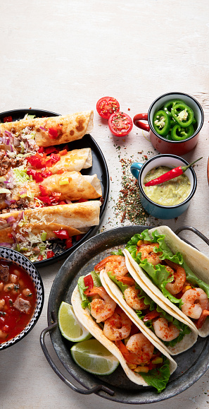 Mexican traditional dishes Tacos with shrimps, meat soup, corn tortillas , tomato salsa on a white background. Top view.