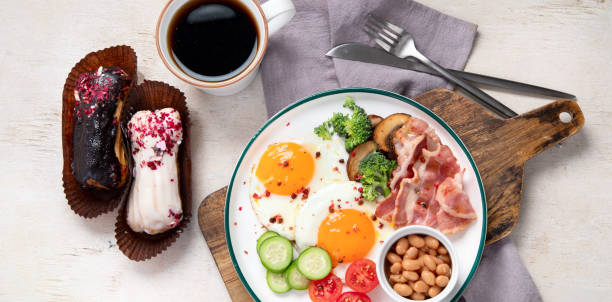 베이컨 스트립, 햇볕이 잘 드는 달걀, 야채, 케이크가 밝은 배경에 있는 전통적인 잉글리스 아침 식사 접시 - englis 뉴스 사진 이미지