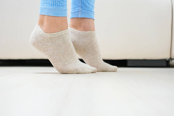 Female legs doing exercises lifting on toes close up, home workout concept.