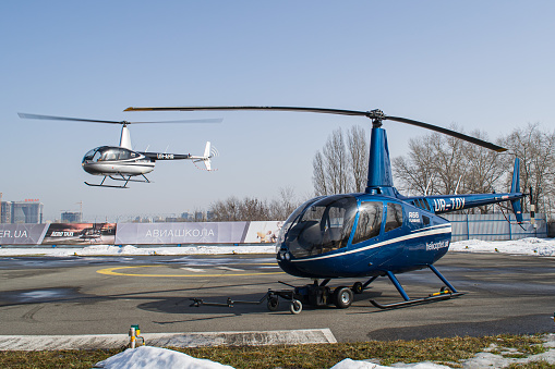Robinson R66 Turbine helicopter standing on the apron with Robinson R44 Raven II in the background landing in Kyiv Challenge Aero Heliport