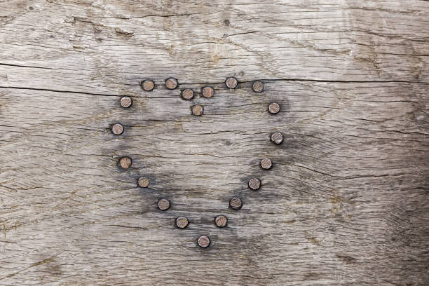 Board of the natural oak wood darkened by time with nails heads in the shape of a heart, which were driven into her, background, texture