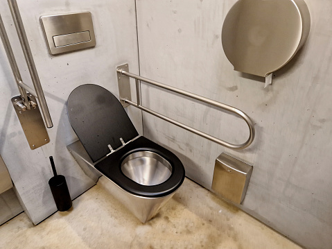 toilet for disabled wheelchair users. a tilting mirror with a lever, and an auxiliary backrest at the toilet bowl. ceramic sink a little lower in sickle height adjustable for a seated person, wc