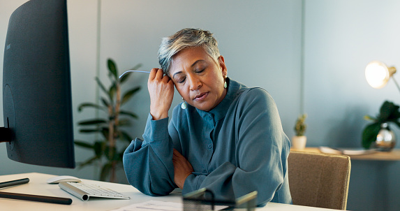 Stress, headache and burnout with a business woman suffering from anxiety while working in her office. Compliance, mental health and migraine with a senior female employee feel frustrated at work