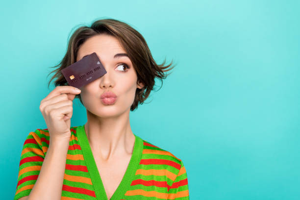 Photo of excited funky woman dressed striped t-shirt holding credit card cover eye isolated turquoise color background stock photo