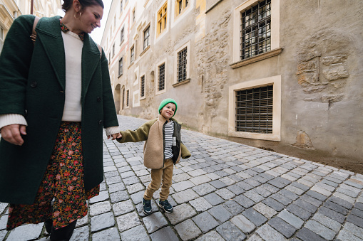 Photo of a young boy and his family exploring streets of a new city and wandering around; he appreciating the view, and being excited to know the new city.