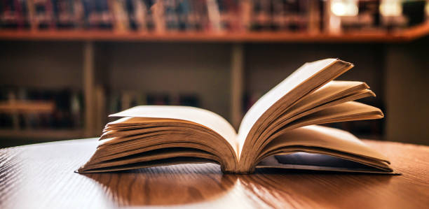 istock Vintage style.An open book or textbook vintage style in the library with light from the window on the reading table and the corridor of the bookshelves in the school classroom background.Education learning concept 1718194075
