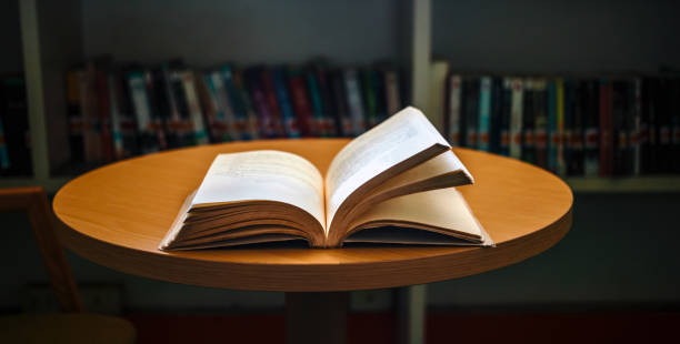 istock Vintage style.An open book or textbook vintage style in the library with light from the window on the reading table and the corridor of the bookshelves in the school classroom background.Education learning concept 1718194088