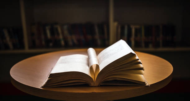 istock Vintage style.An open book or textbook vintage style in the library with light from the window on the reading table and the corridor of the bookshelves in the school classroom background.Education learning concept 1718194099