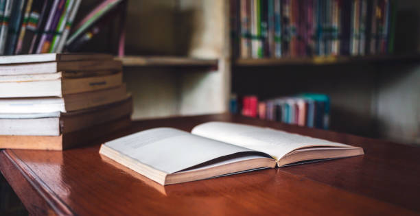 istock Vintage style.An open book or textbook vintage style in the library with light from the window on the reading table and the corridor of the bookshelves in a Stack of books background.Education learning concept 1718194106