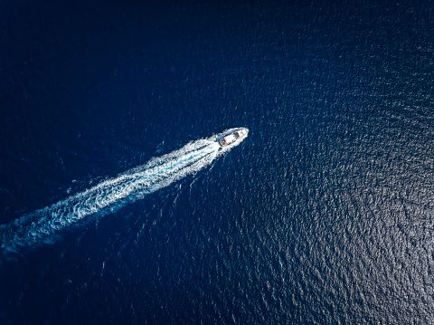 High aerial view of a luxury yacht traveling over the sparkling ocean