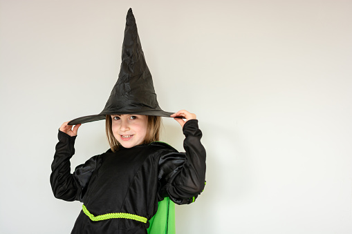 Smiling girl dressed up as a witch against white background