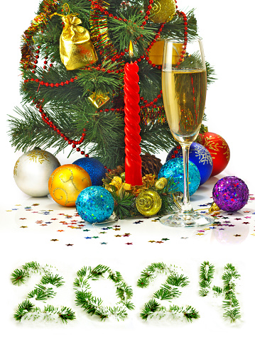 Glass of red wine with gold Christmas ornaments and ribbon around the stem on a white background.